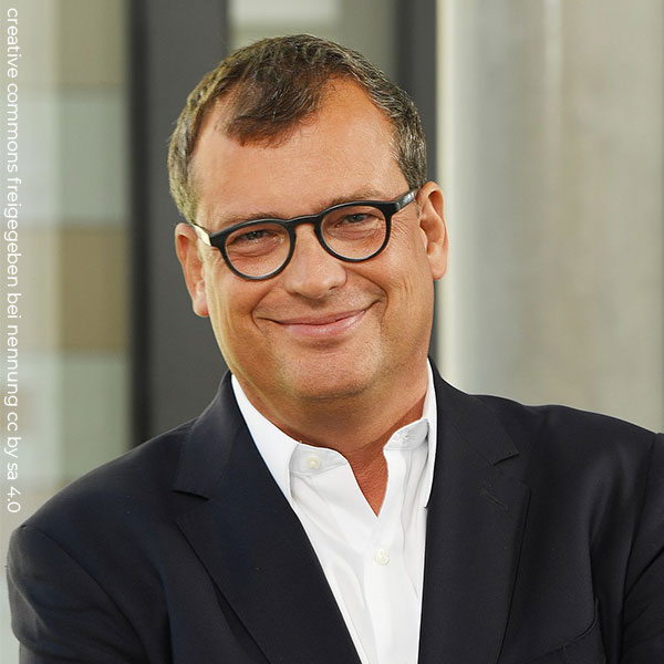 Person weiß, Portrait männlich gelesen, braune Haare, lächelnd, schwarzes Sakko
